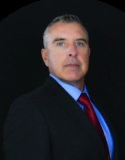 A man in a suit and tie is standing in front of a black background
