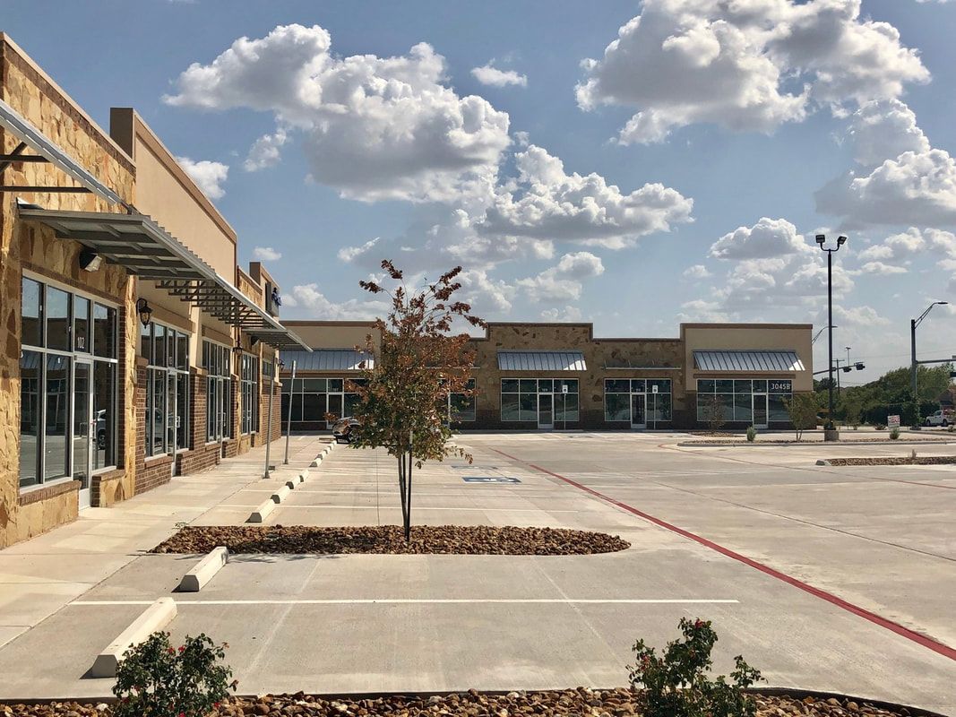 A row of buildings with a parking lot in front of them.