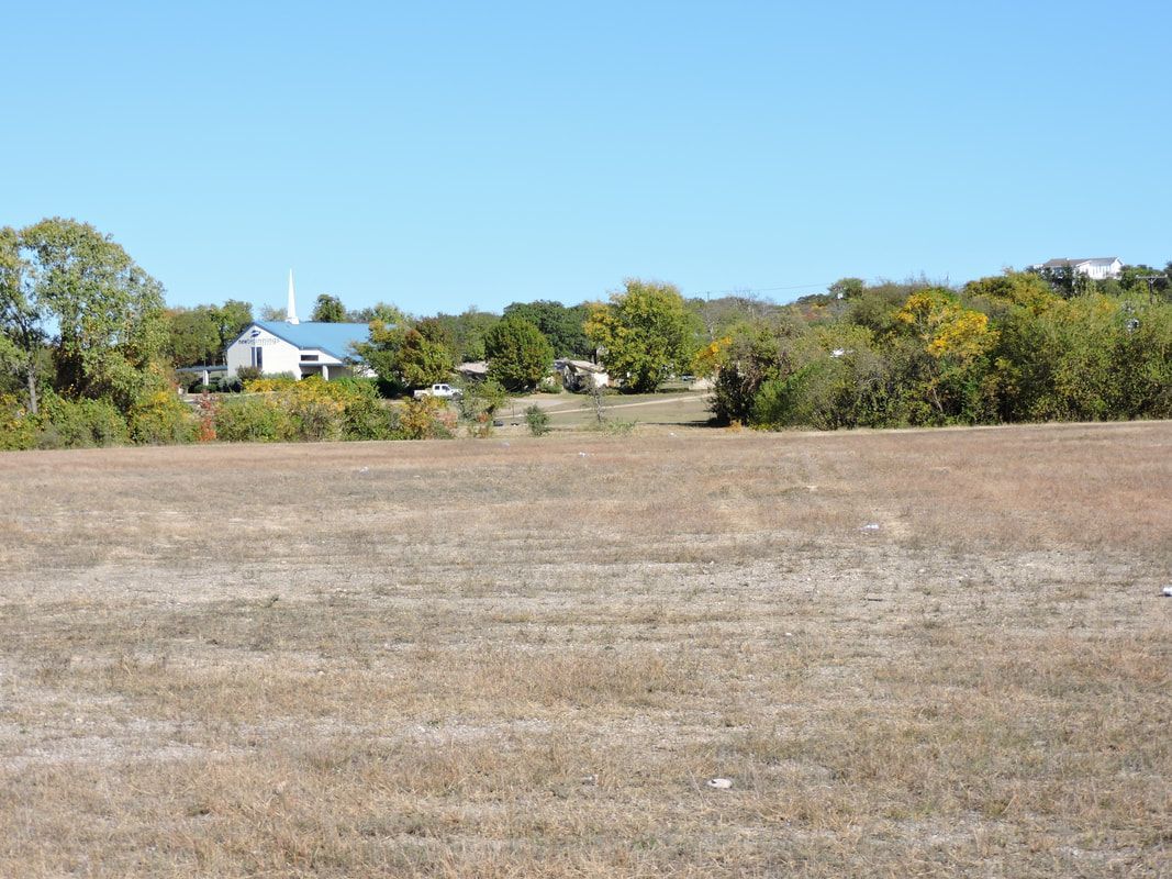 A large empty field with a church in the background.