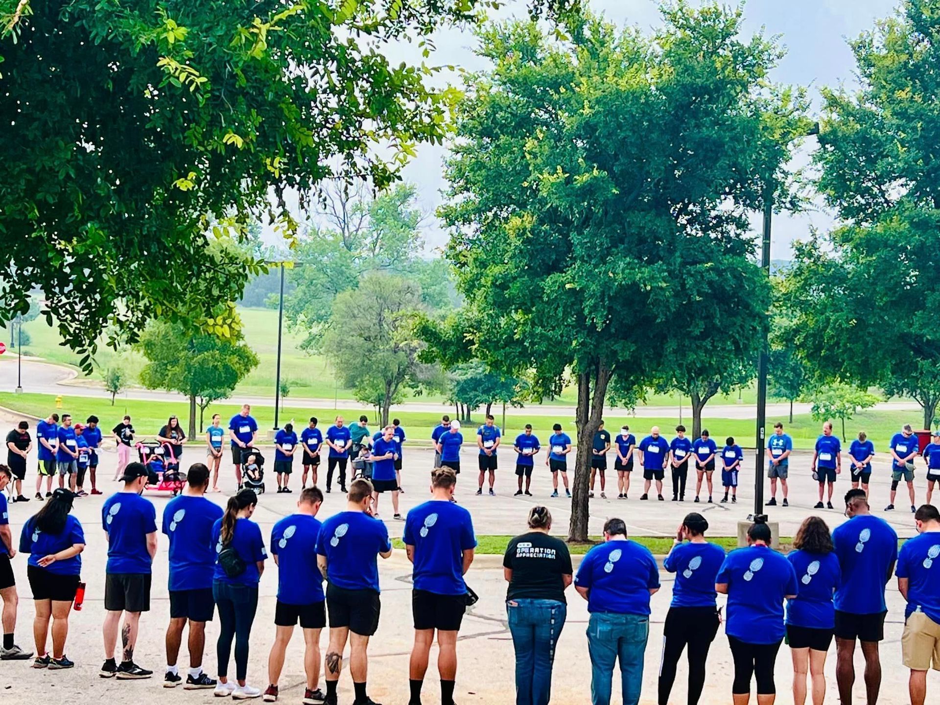 A group of people in blue shirts are standing in a circle.