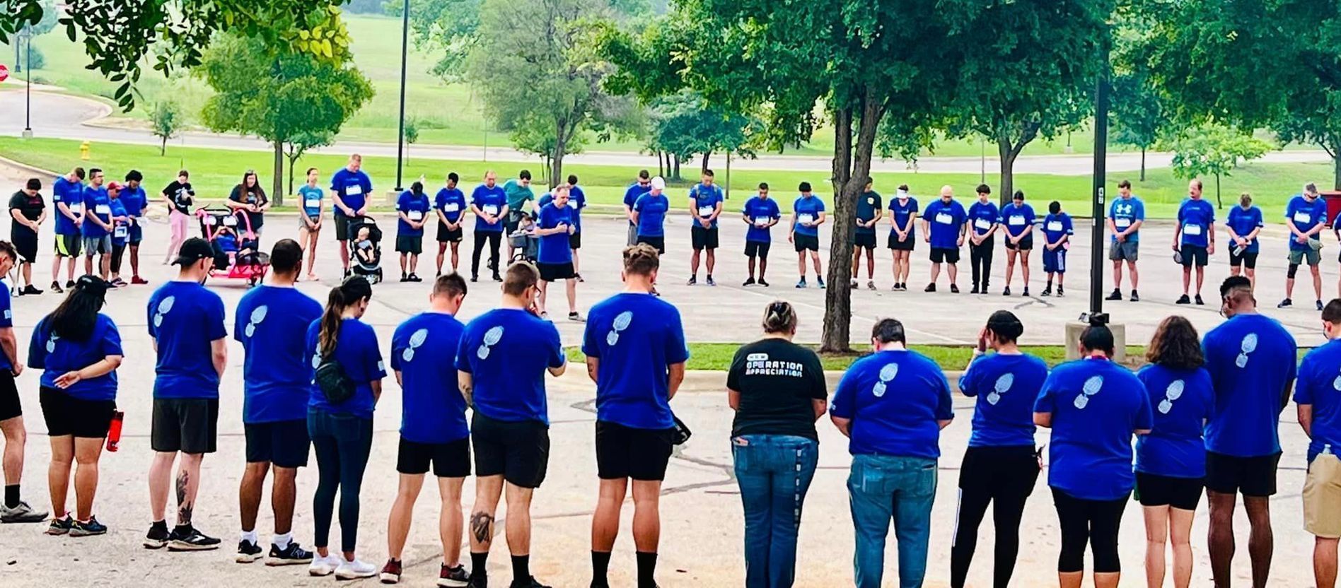 A group of people wearing blue shirts are standing in a line.