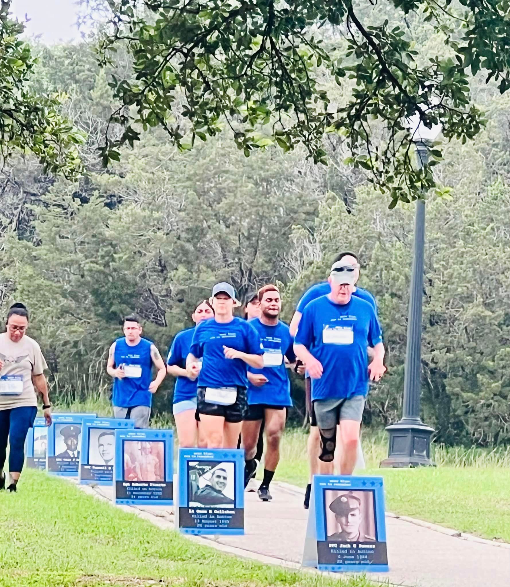 A group of people in blue shirts are running down a path.