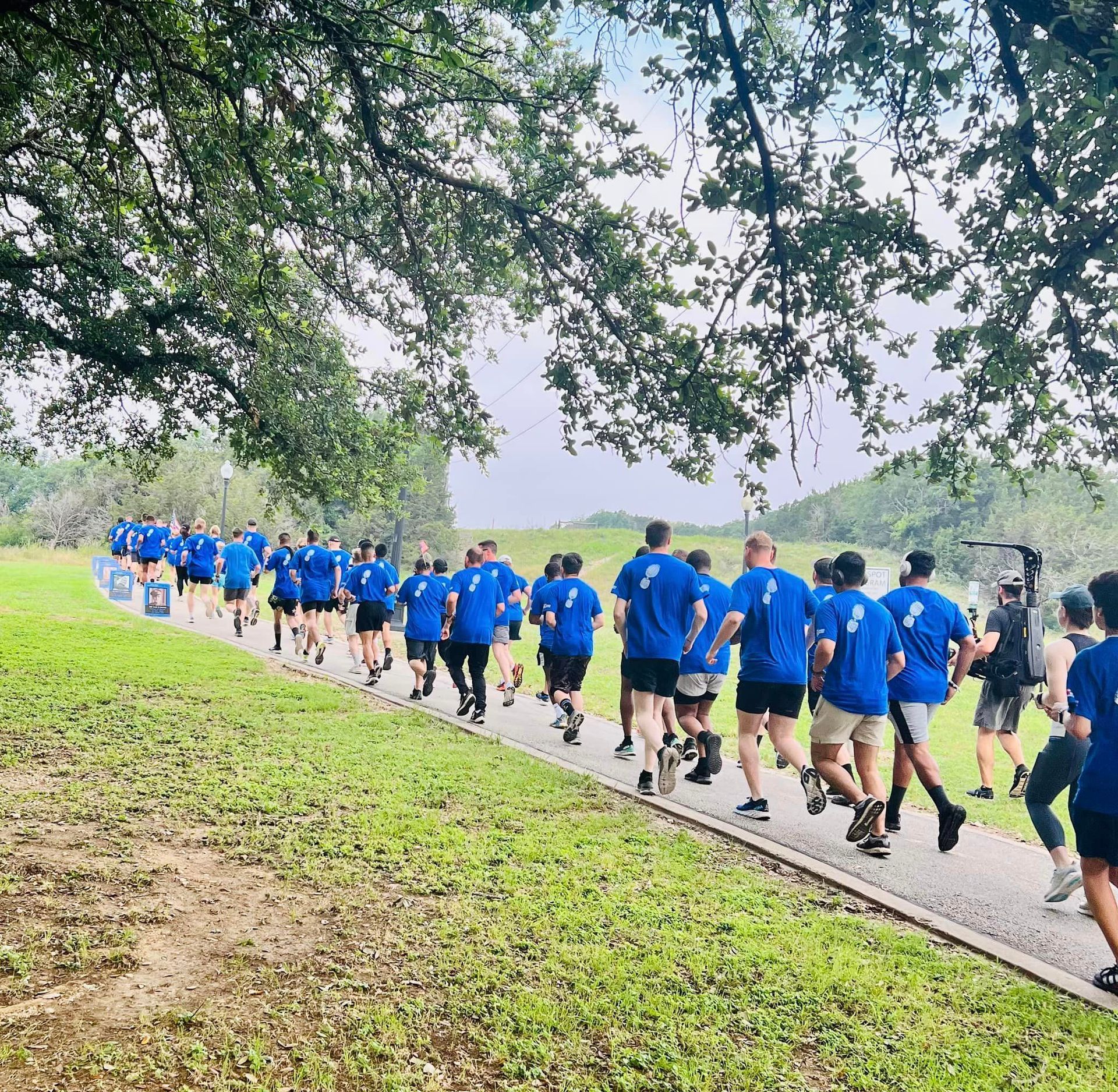 A group of people are running down a path in a park.