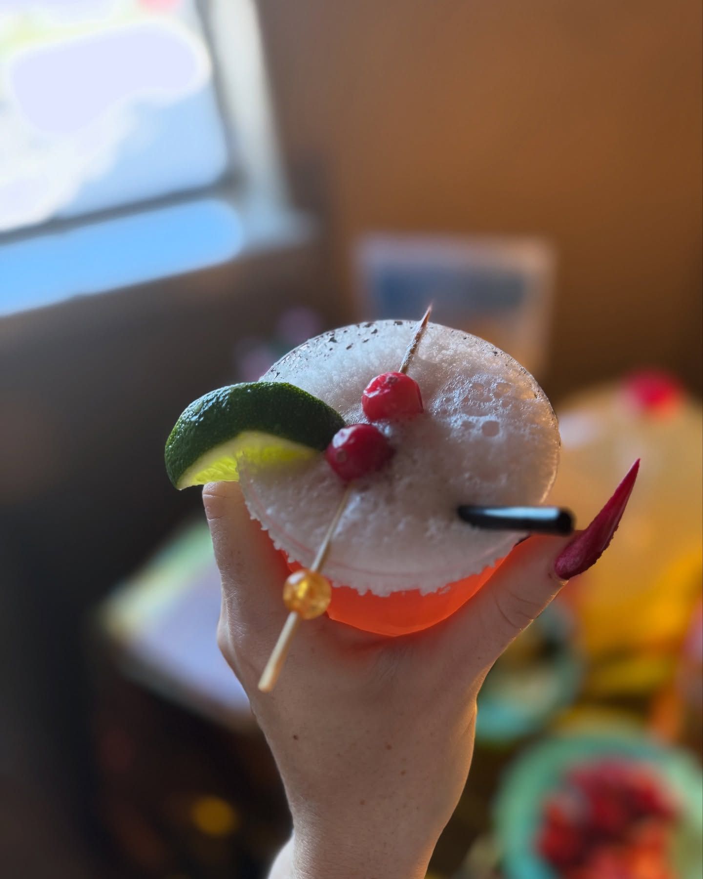 A person is holding a drink in their hand with a cherry on top.