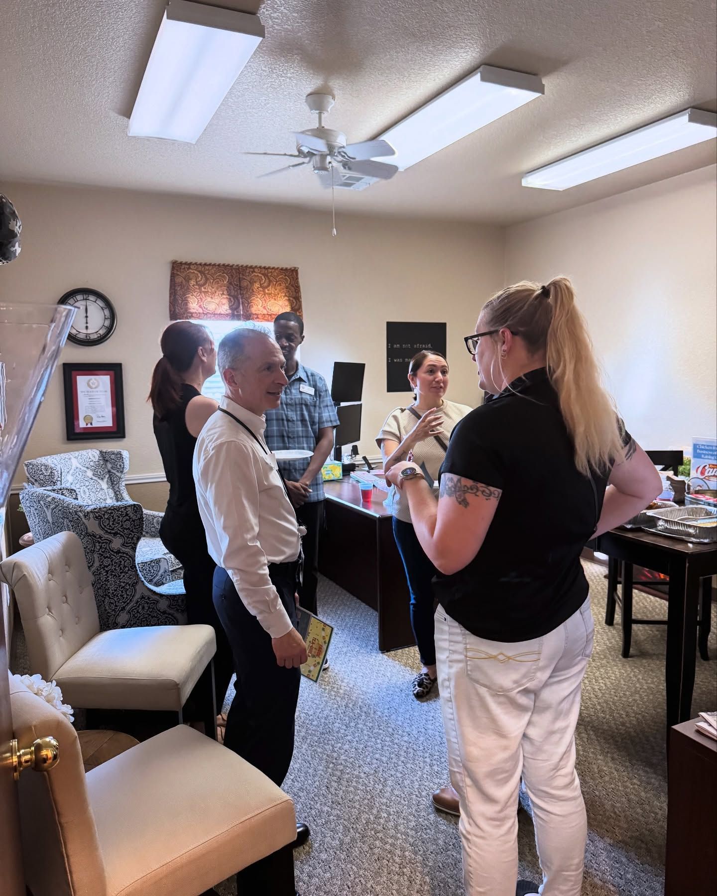 A group of people are standing in a room talking to each other.