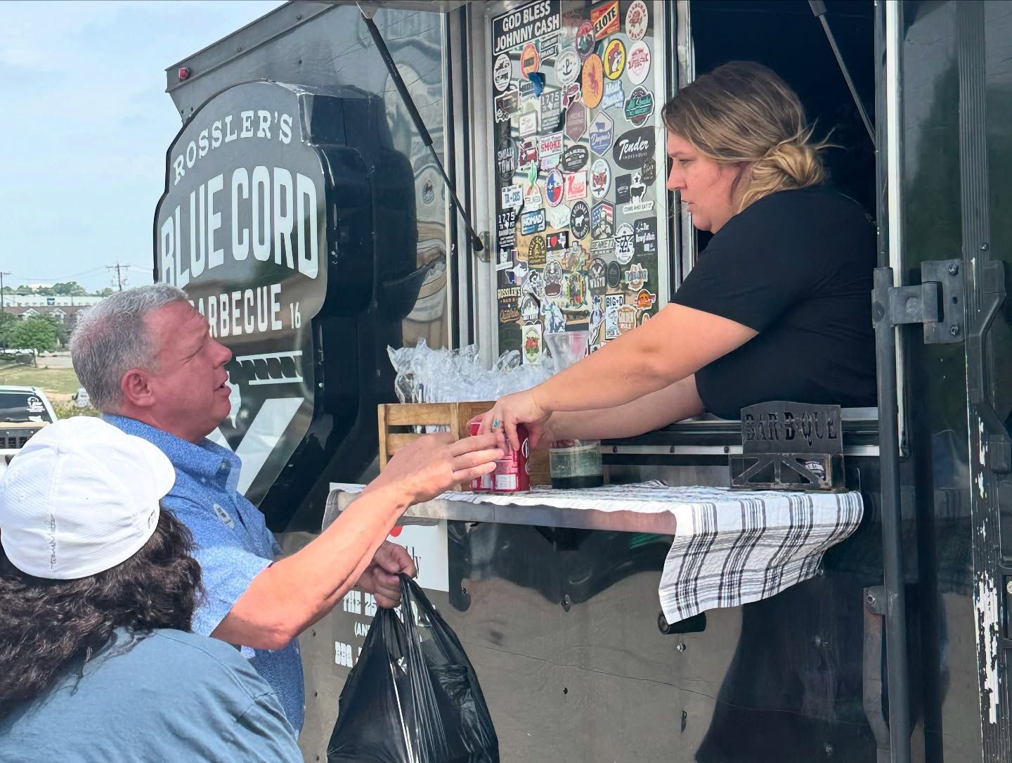 A man and a woman are standing in front of a food truck.
