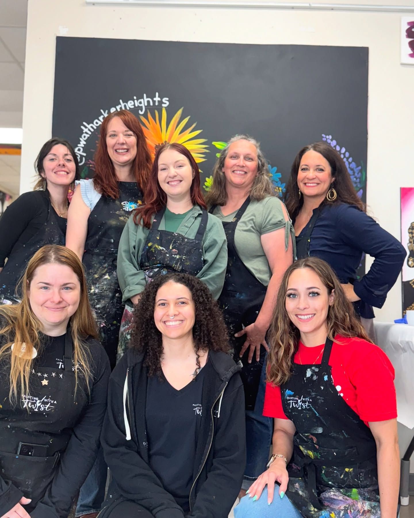 A group of women are posing for a picture in front of a blackboard.