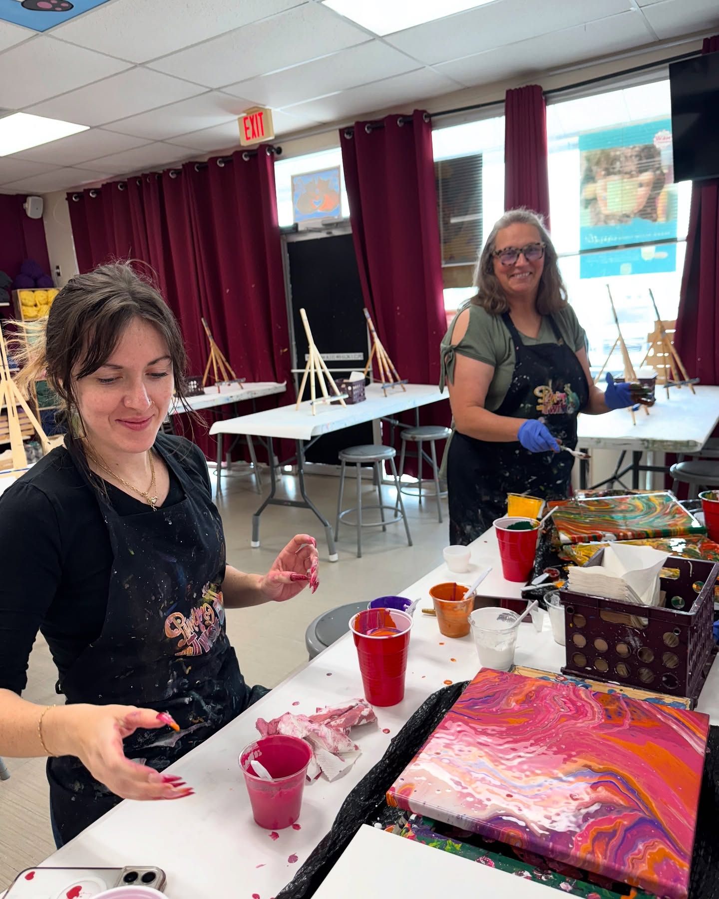 Two women are sitting at a table painting.