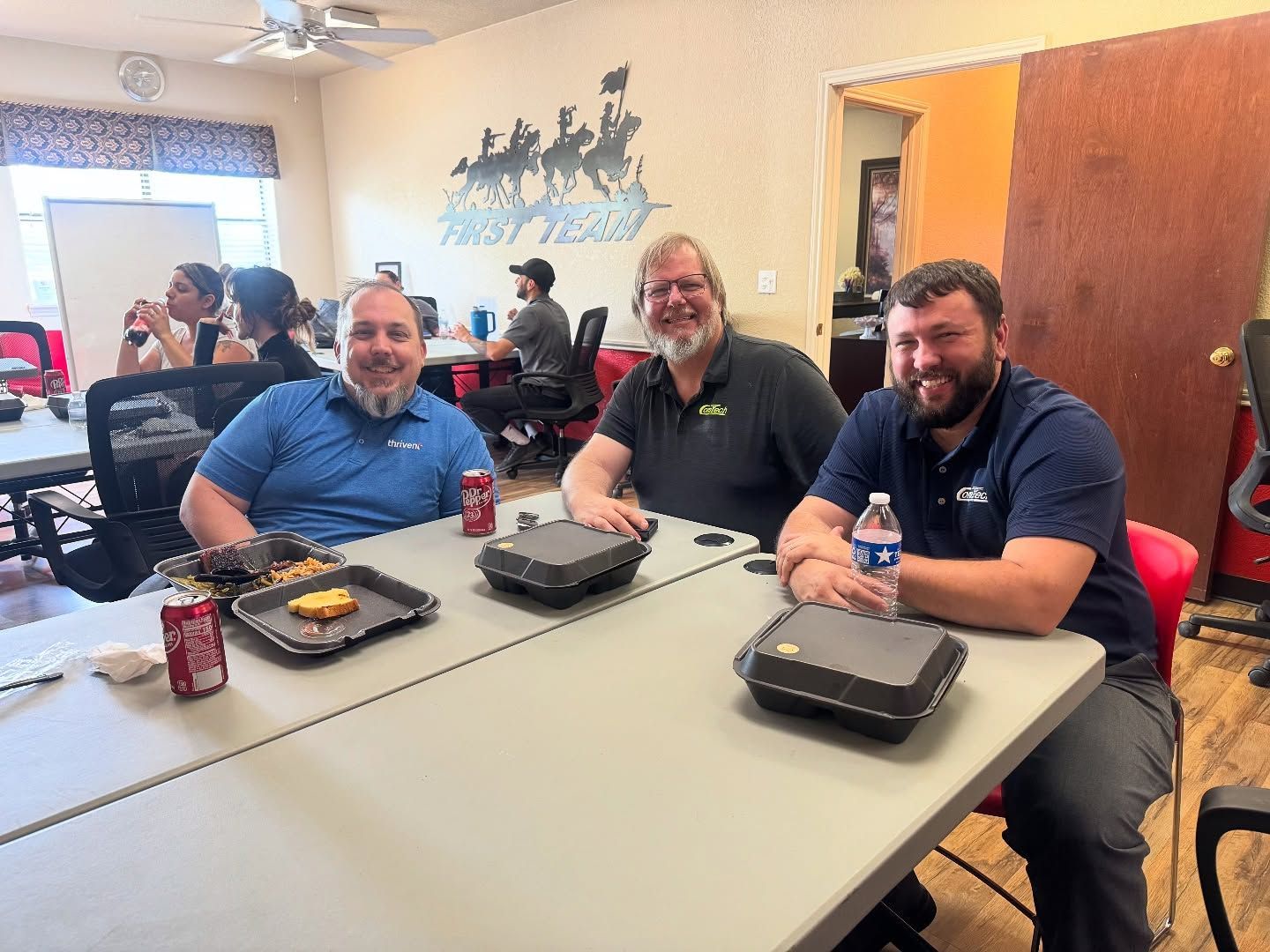 A group of men are sitting at a table with food and drinks.