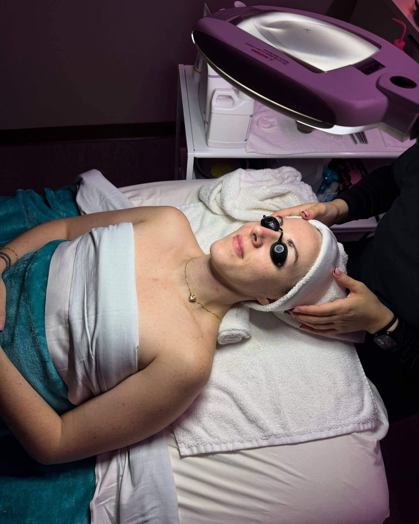A woman is laying on a bed getting a facial treatment