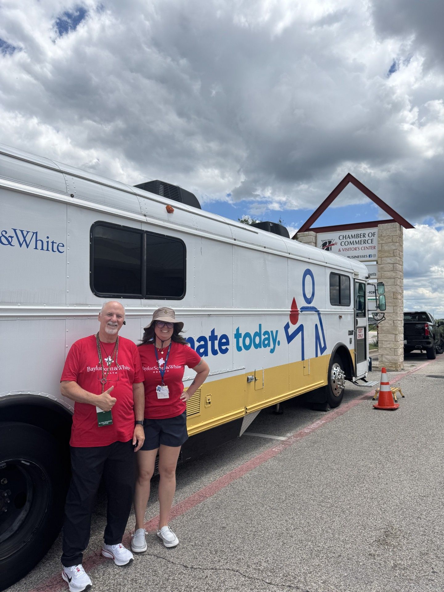A man and a woman are standing in front of a bus that says donate today.