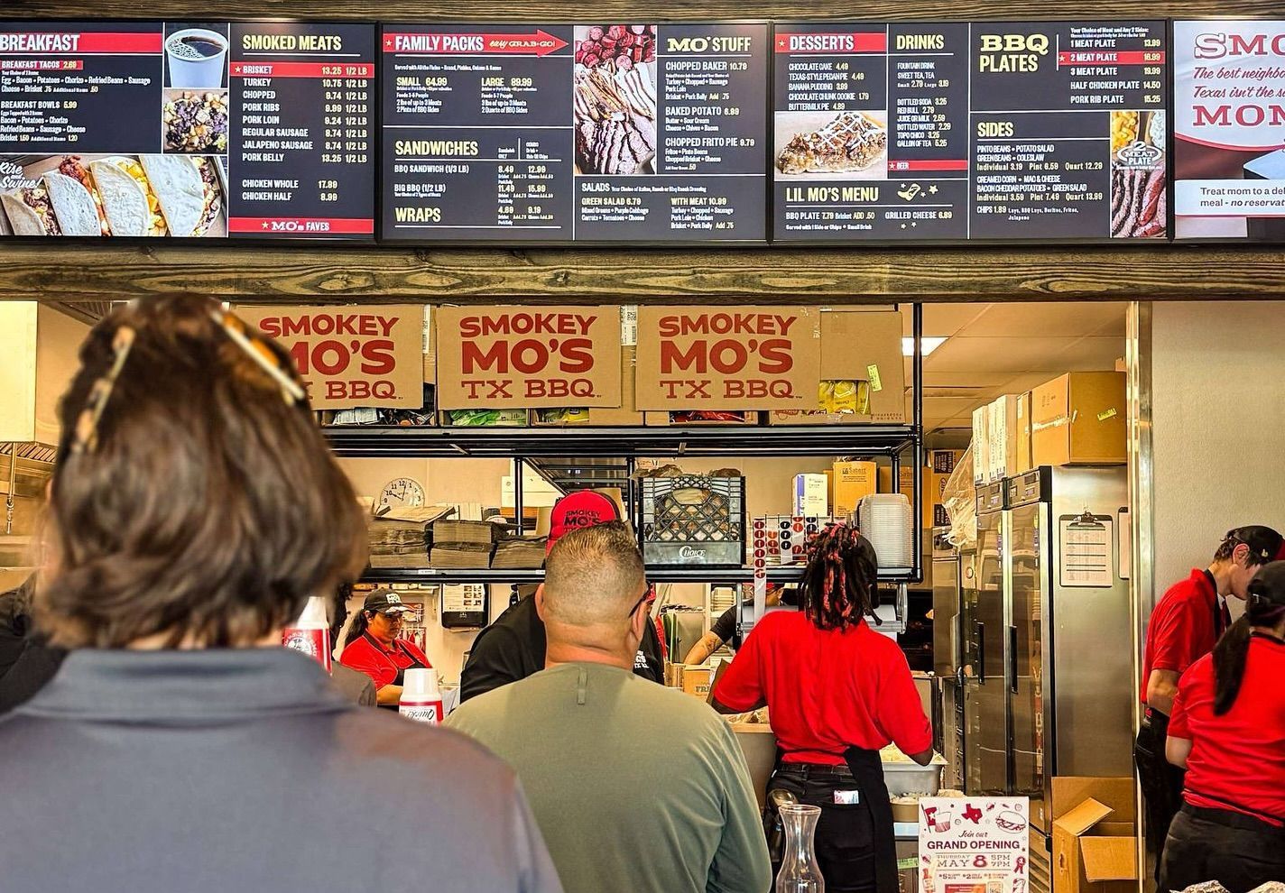 A group of people are standing in line at a restaurant.