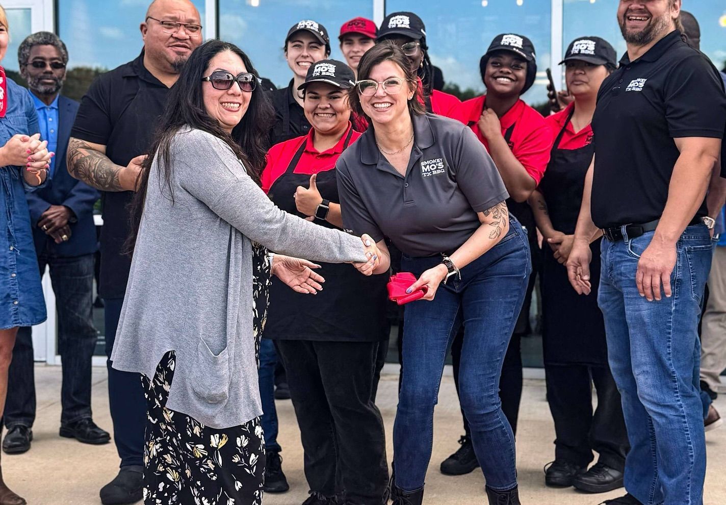 A group of people are standing in front of a building shaking hands.