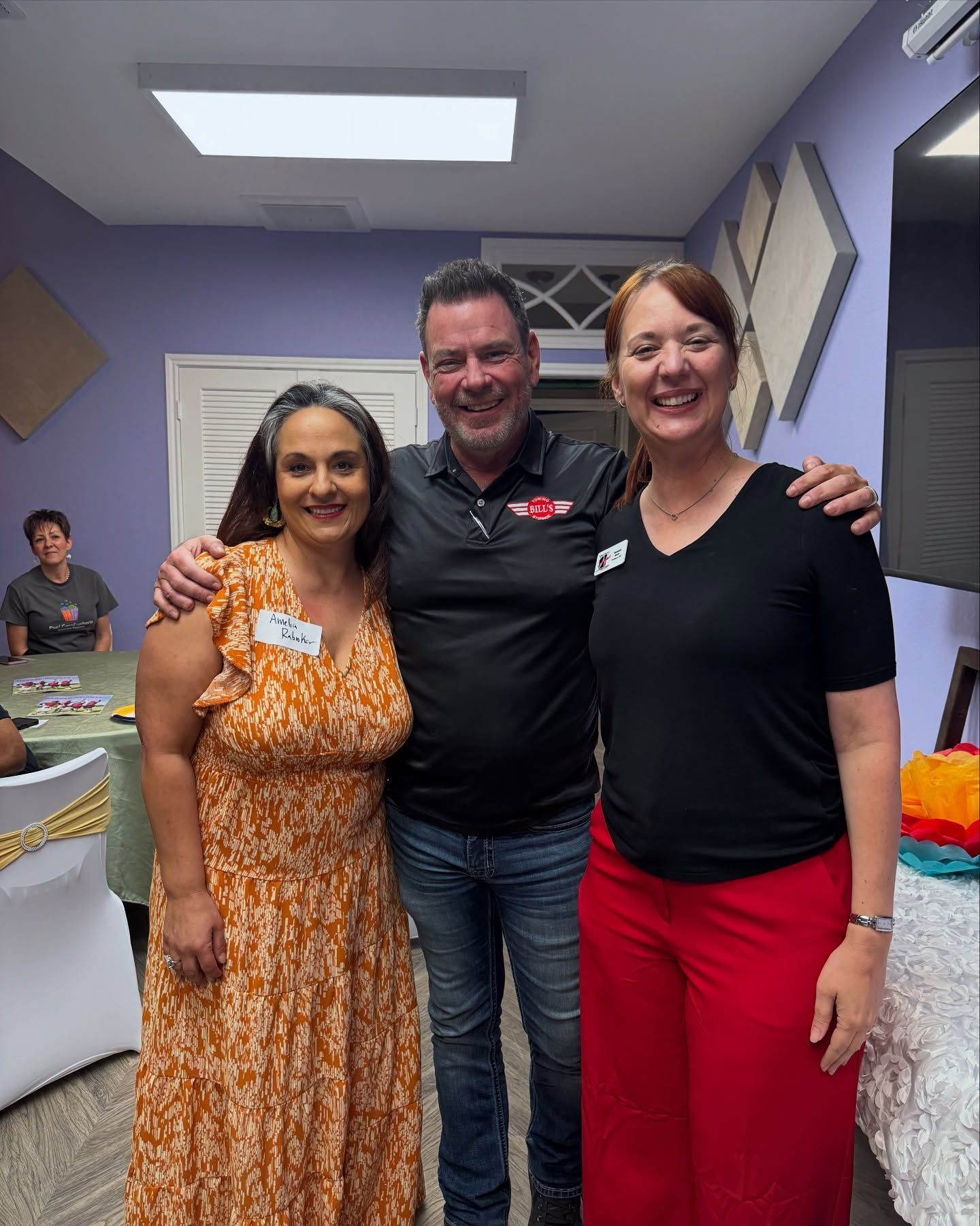 A man and two women are posing for a picture in a room.