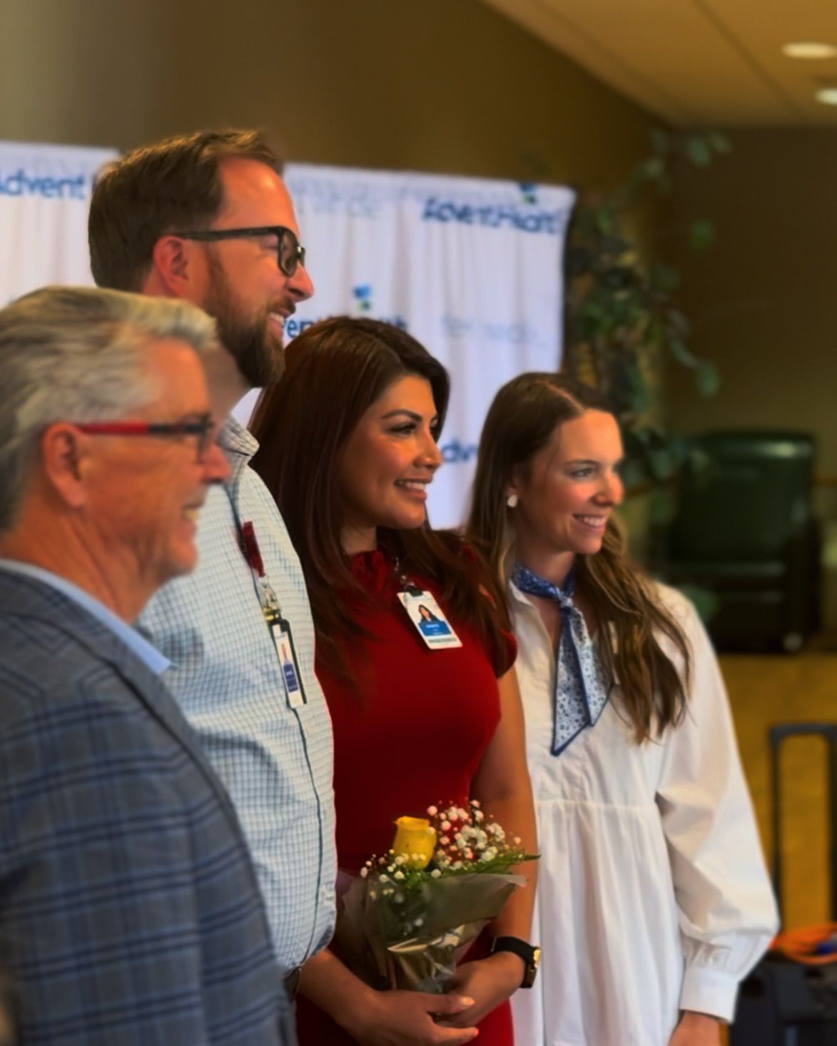 A group of people standing next to each other with one woman holding a bouquet of flowers