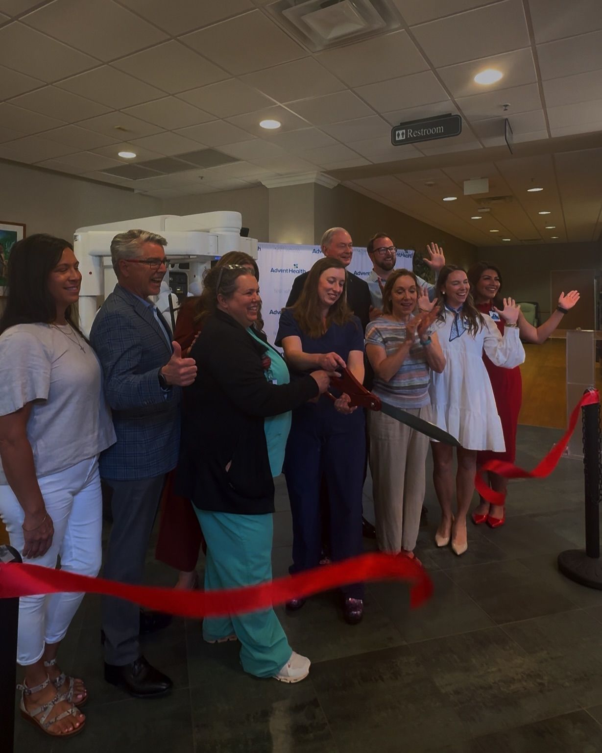 A group of people are cutting a red ribbon