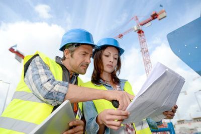 A man and a woman are looking at a blueprint on a construction site.