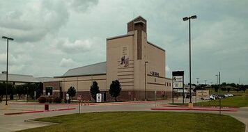 A large building is sitting in the middle of a parking lot.