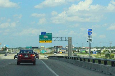 A red car is driving down a highway next to a sign that says 190