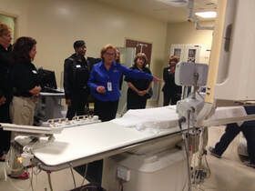 A group of people are standing around a hospital bed.