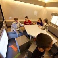 A group of children are sitting around a table in a room.