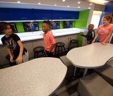 A group of children are standing around a table in a kitchen.