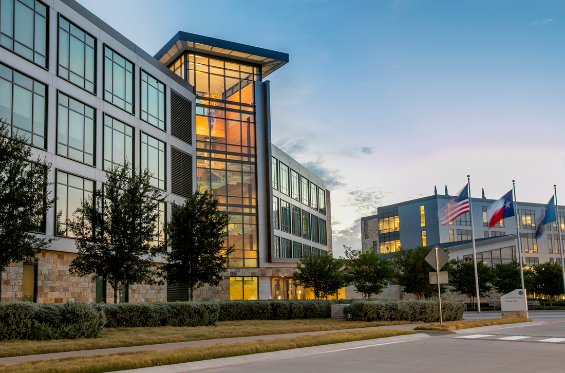 A large building with a lot of windows and flags in front of it.