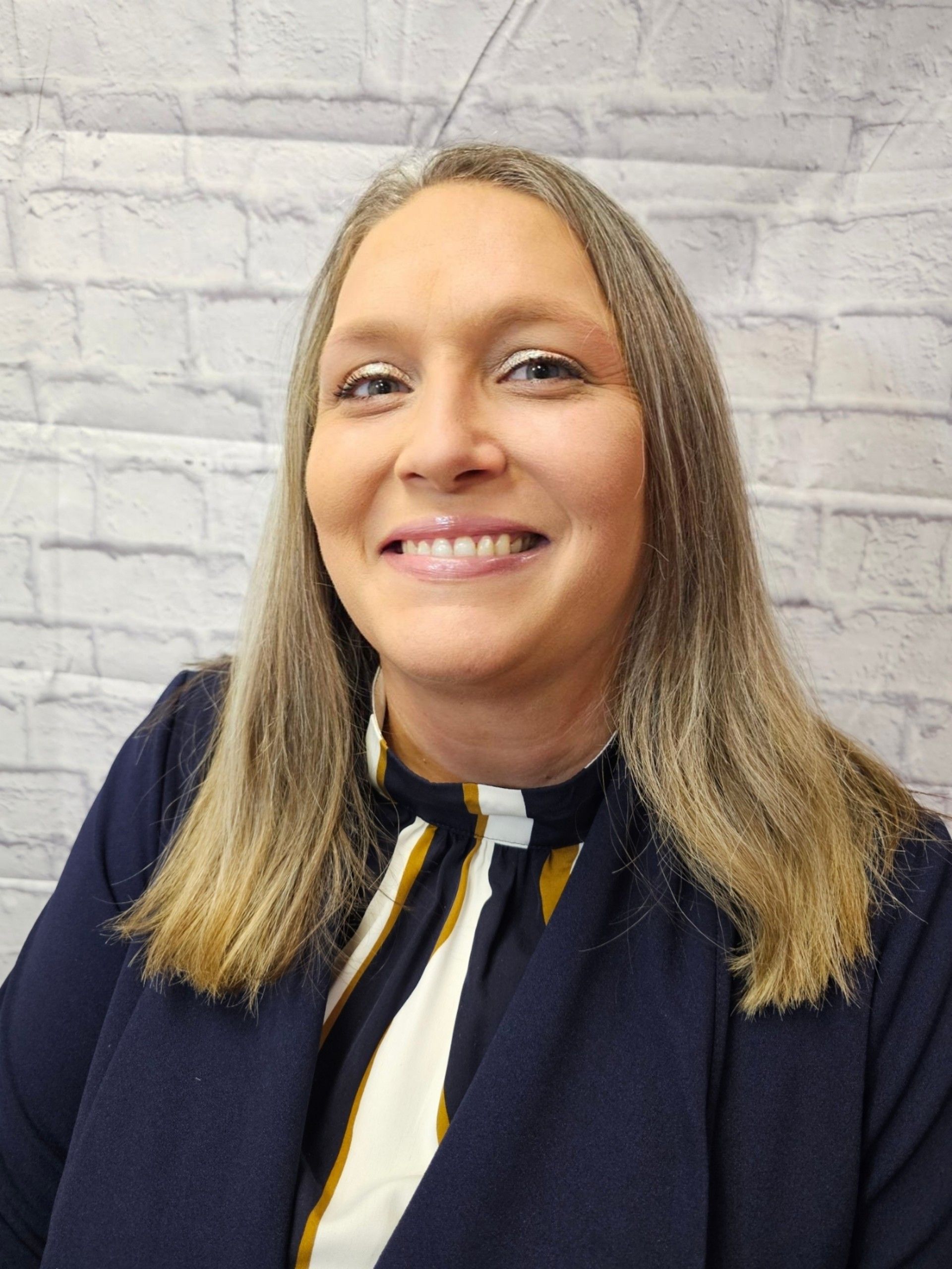 A woman is wearing a black and white plaid jacket and smiling.
