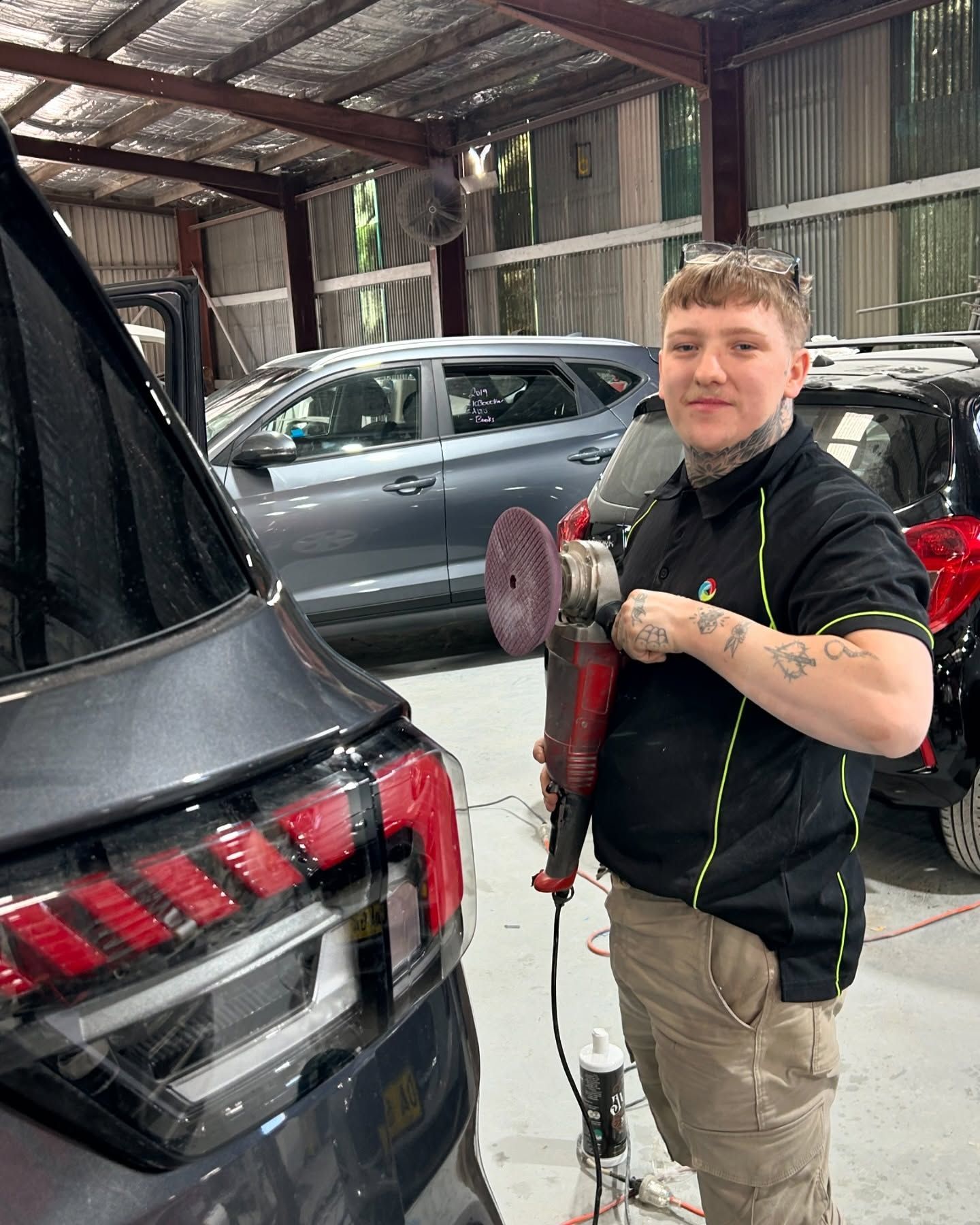 A man is polishing a car in a garage.