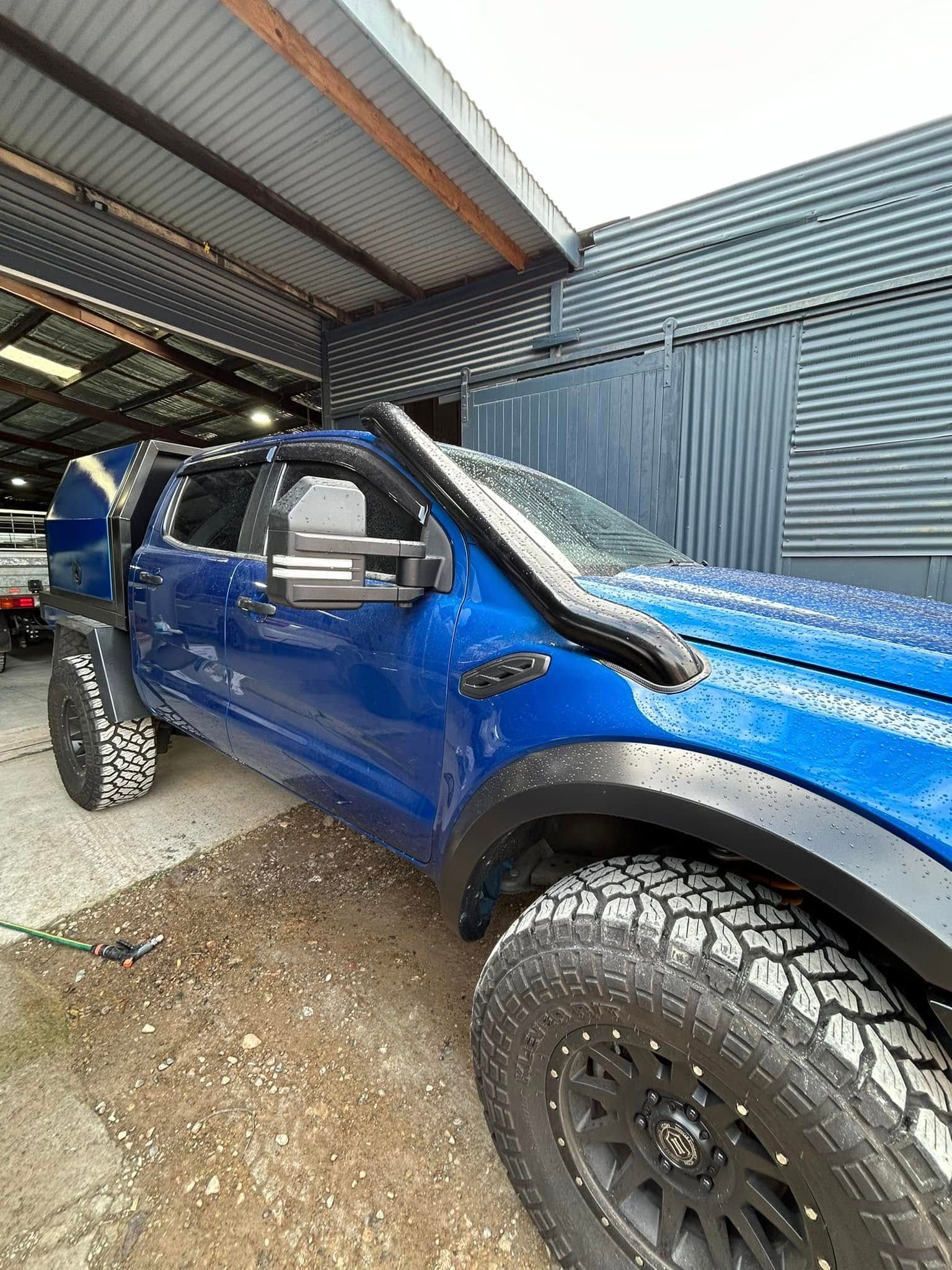 A blue truck is parked in front of a building.