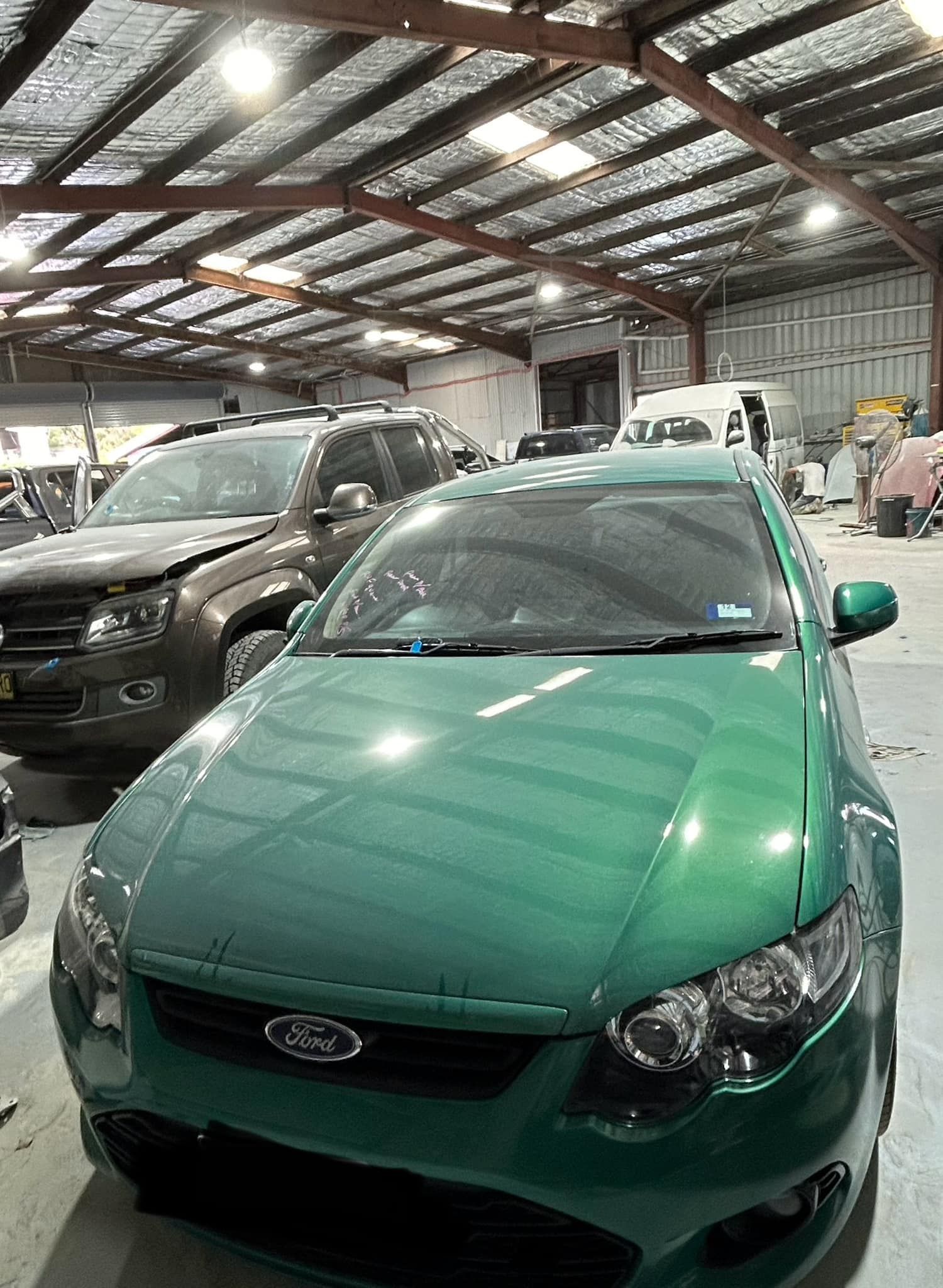 A green ford car is parked in a garage.
