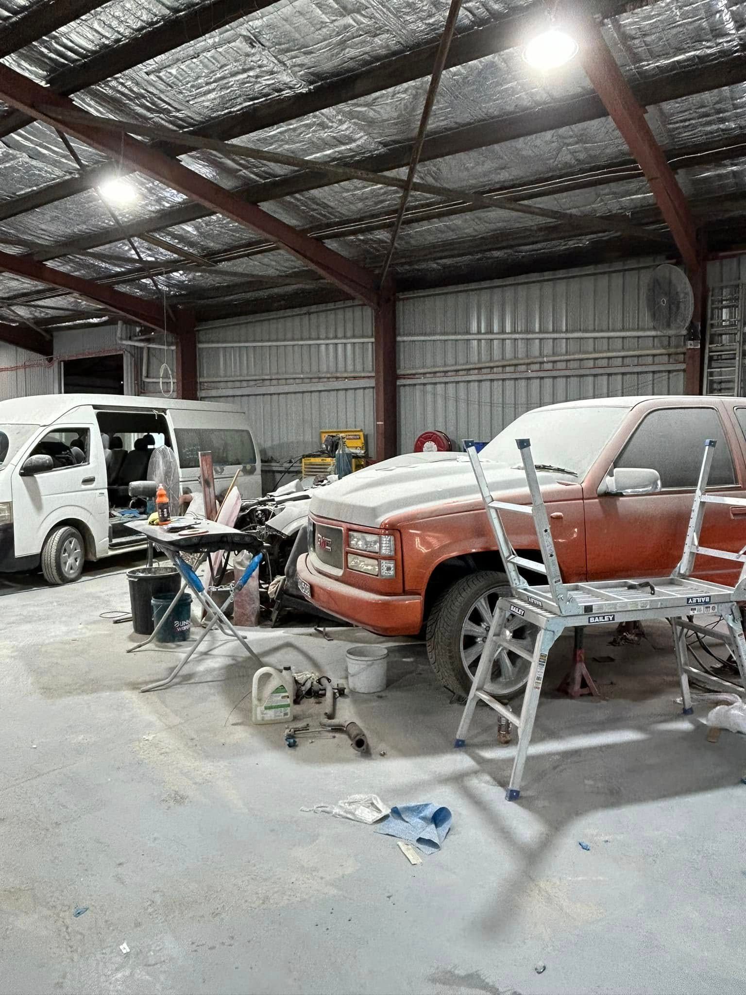A row of cars are parked inside of a warehouse.