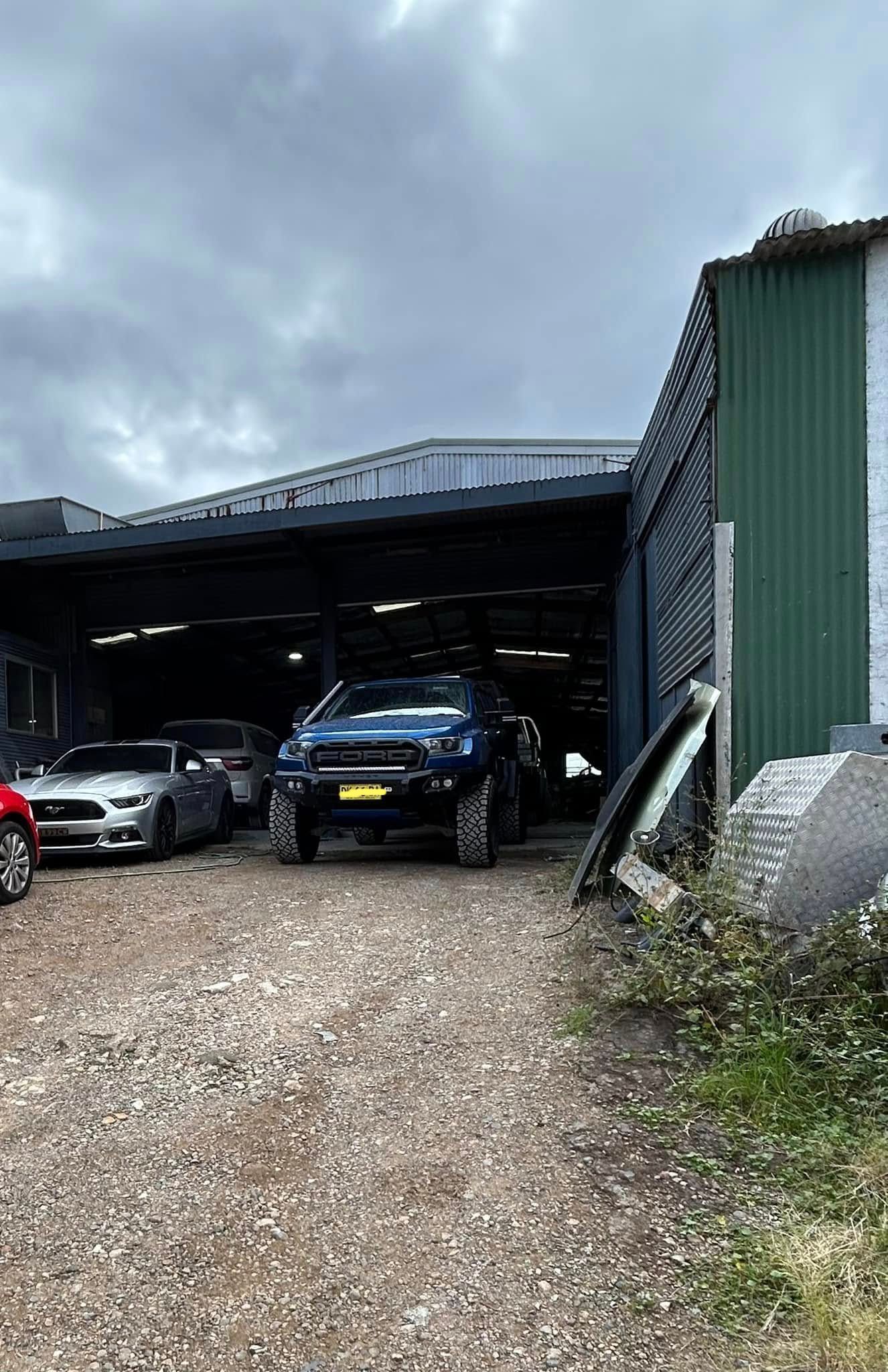 A blue truck is parked in front of a garage.