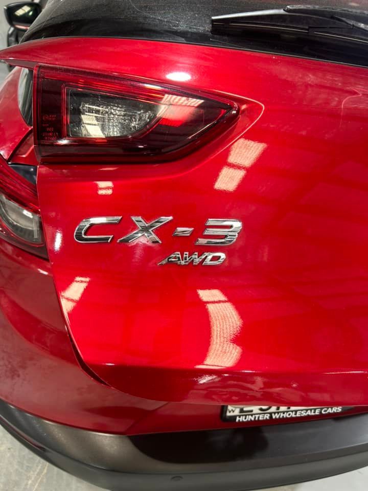 A red mazda cx 3 is parked in a garage.