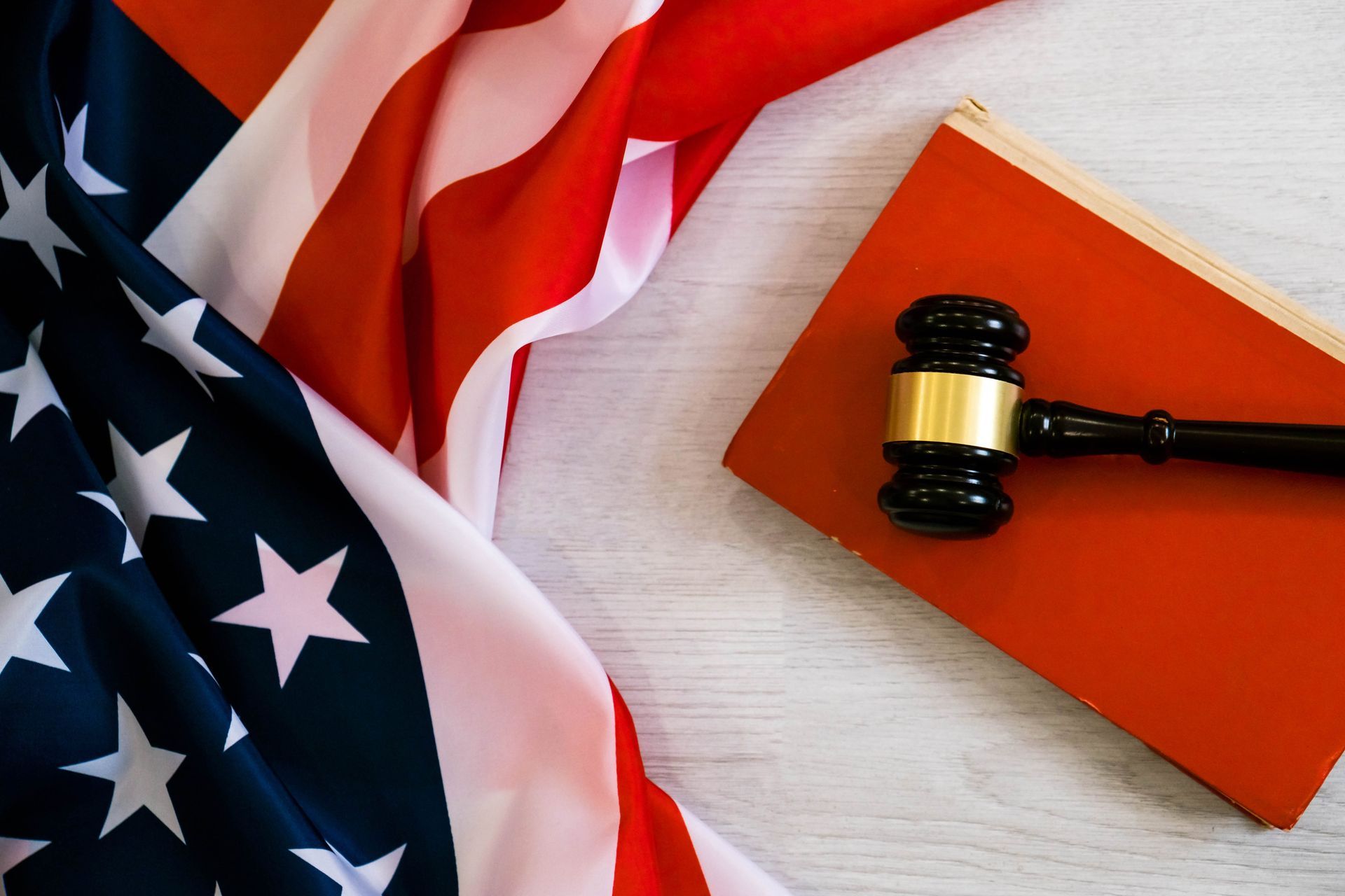 American flag with judge’s gavel resting on a red book or folder