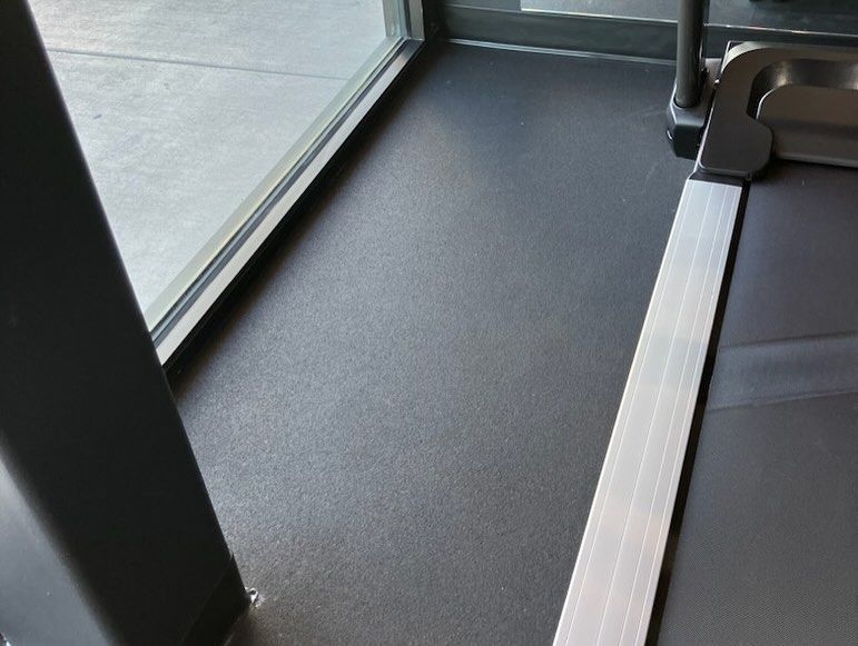 A treadmill is sitting next to a window in a gym