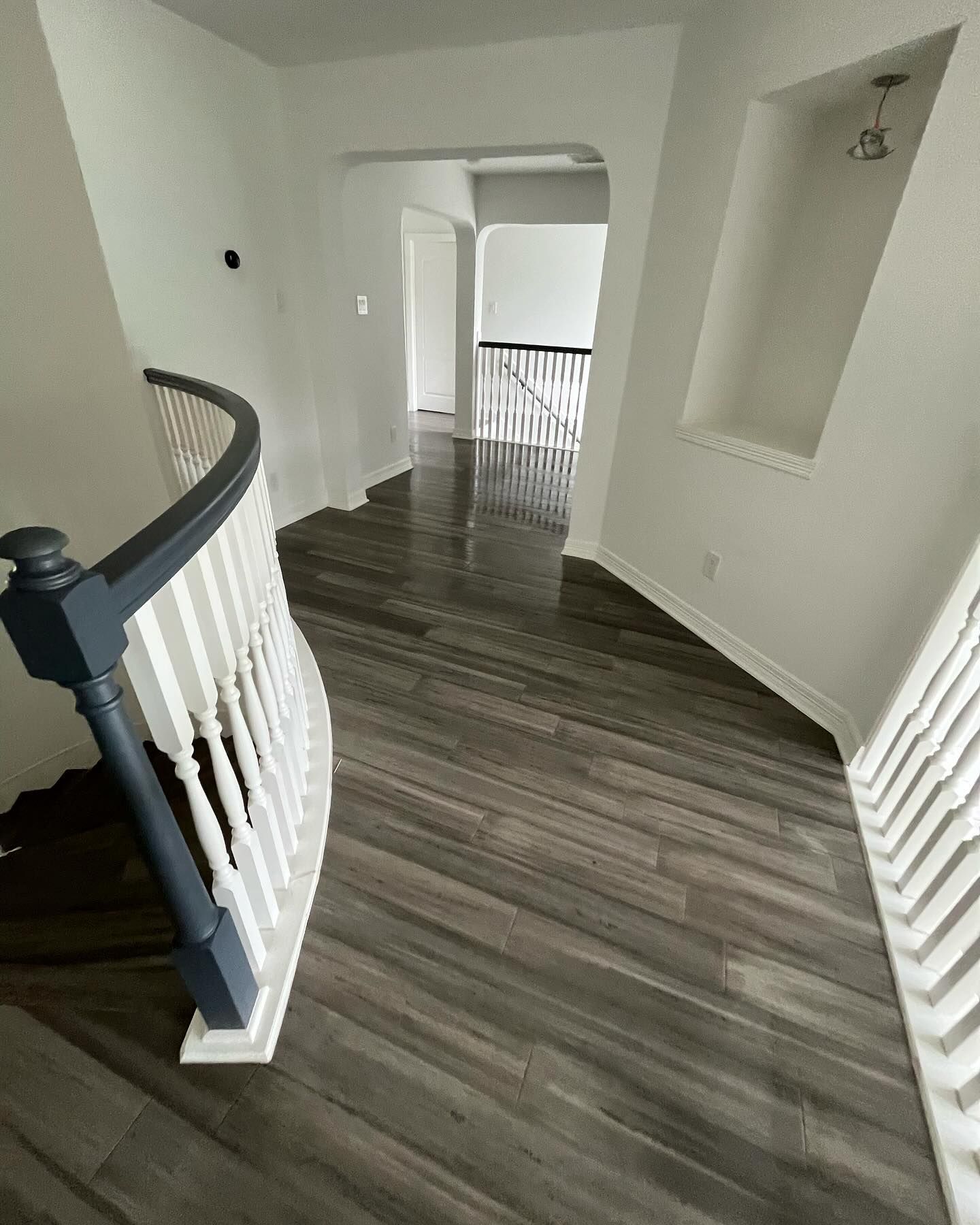 A hallway with stairs and a railing in a house.