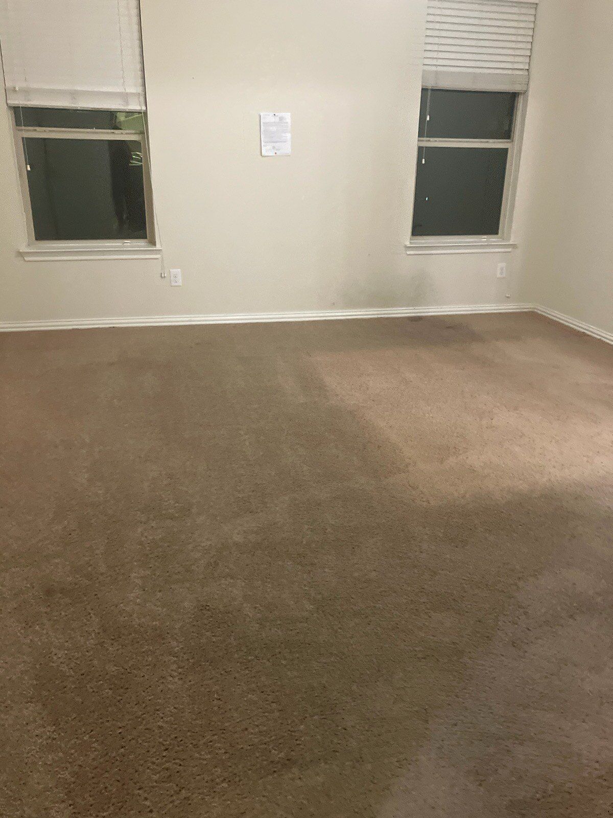 An empty room with two windows and a carpeted floor.
