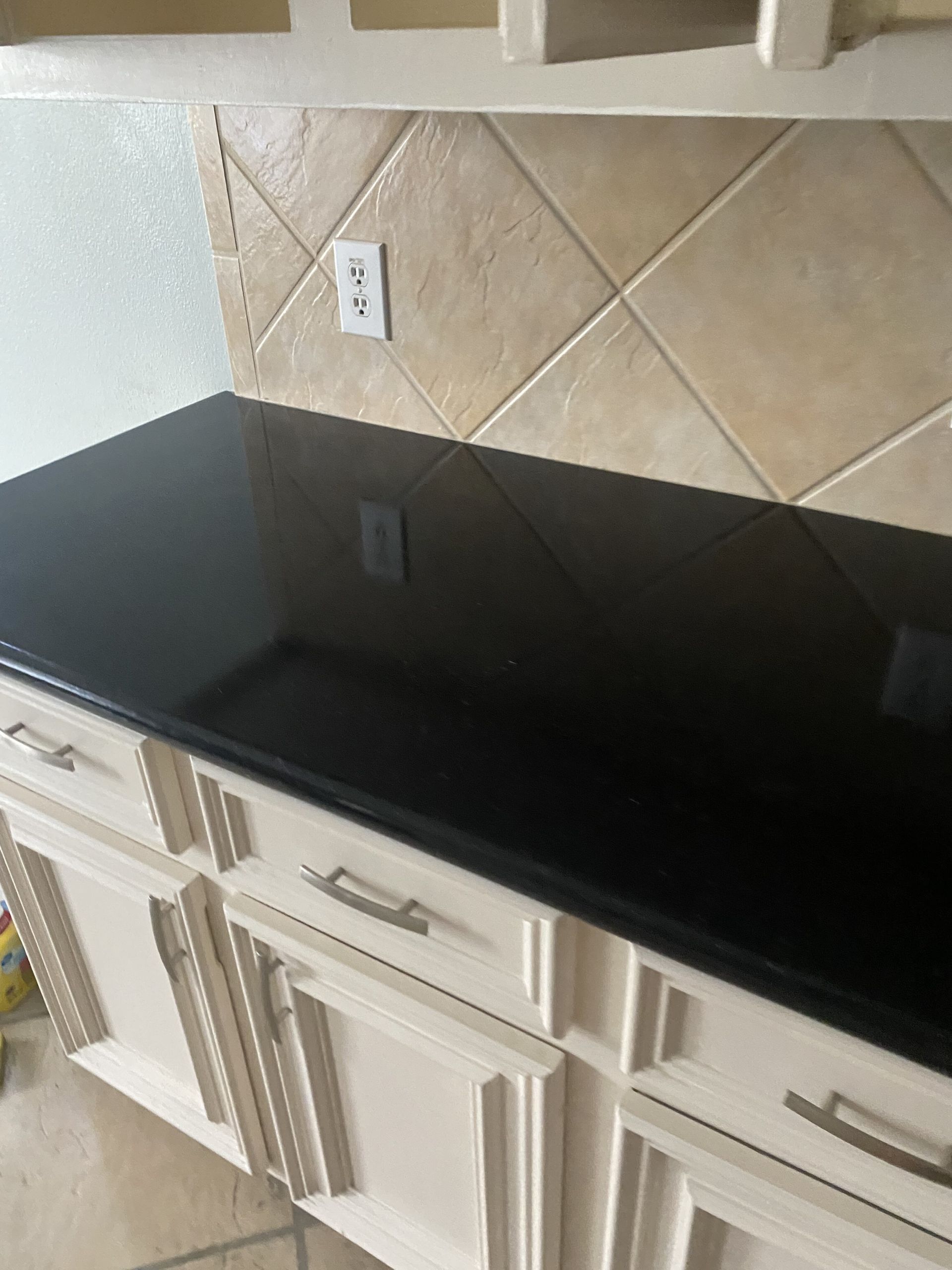 A black counter top in a kitchen with white cabinets