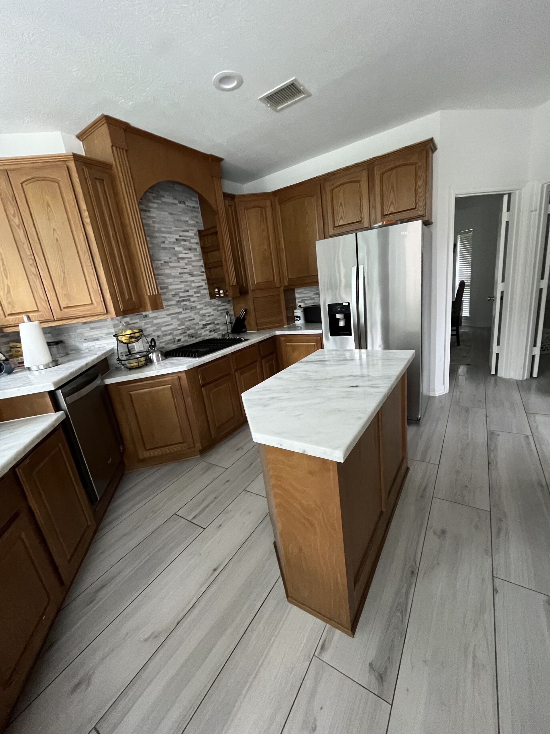 A kitchen with wooden cabinets and a marble counter top