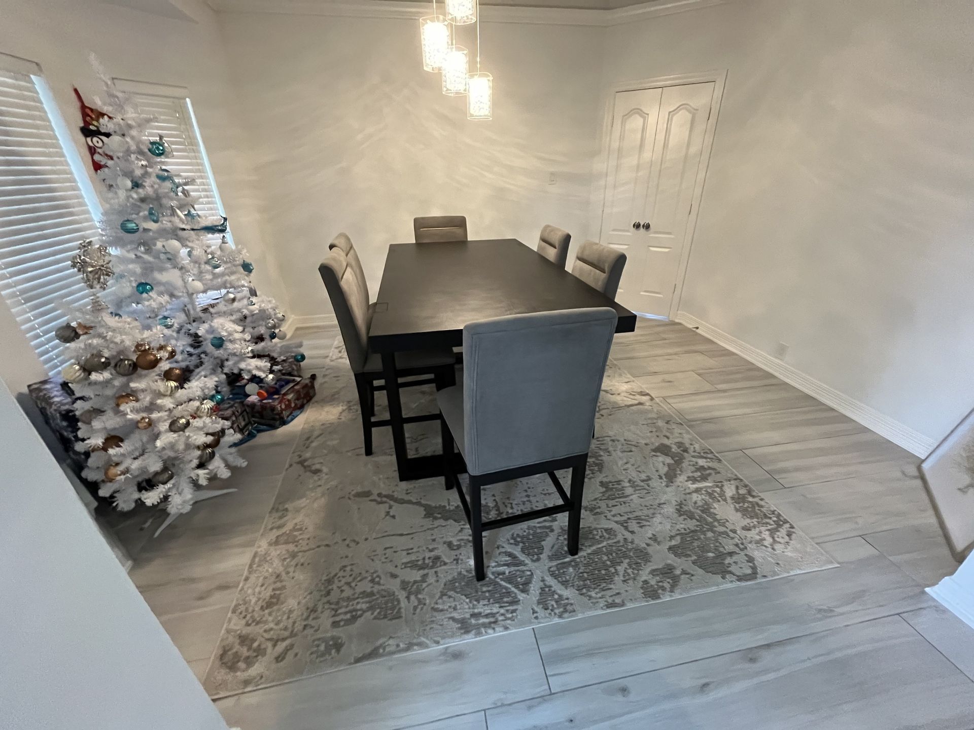 A dining room with a table and chairs and a christmas tree.