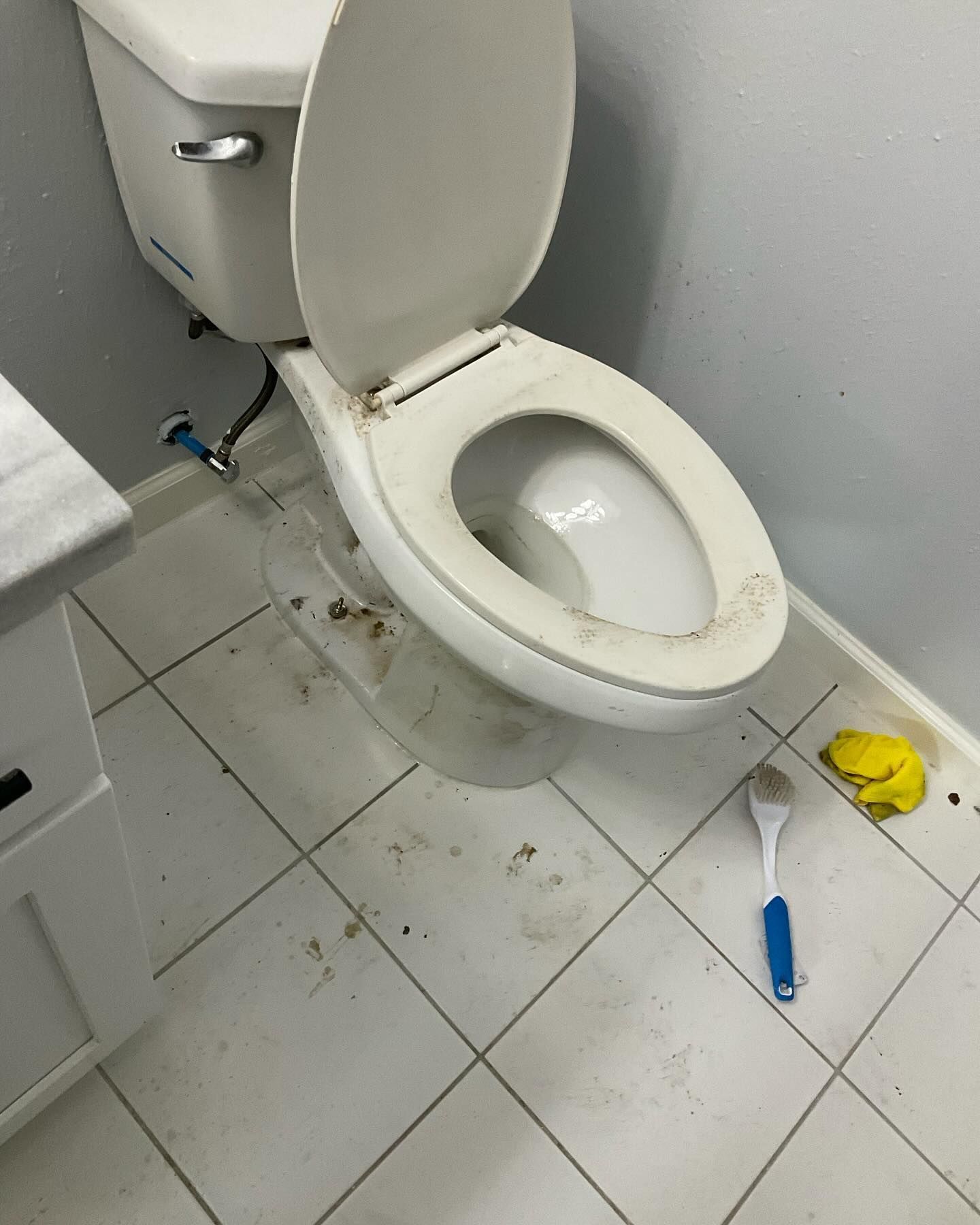 A toilet is sitting on a tiled floor in a bathroom.