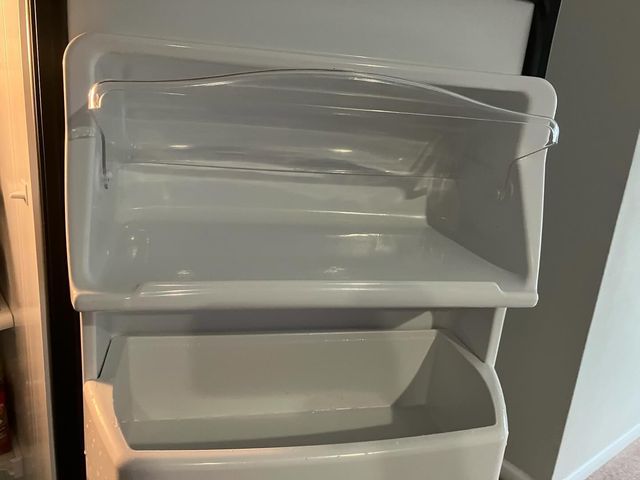 Empty refrigerator door shelves, white plastic, angled view.