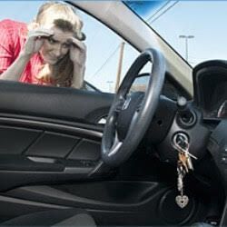 Woman locked out of her car looking through the window at the keys in the ignition.
