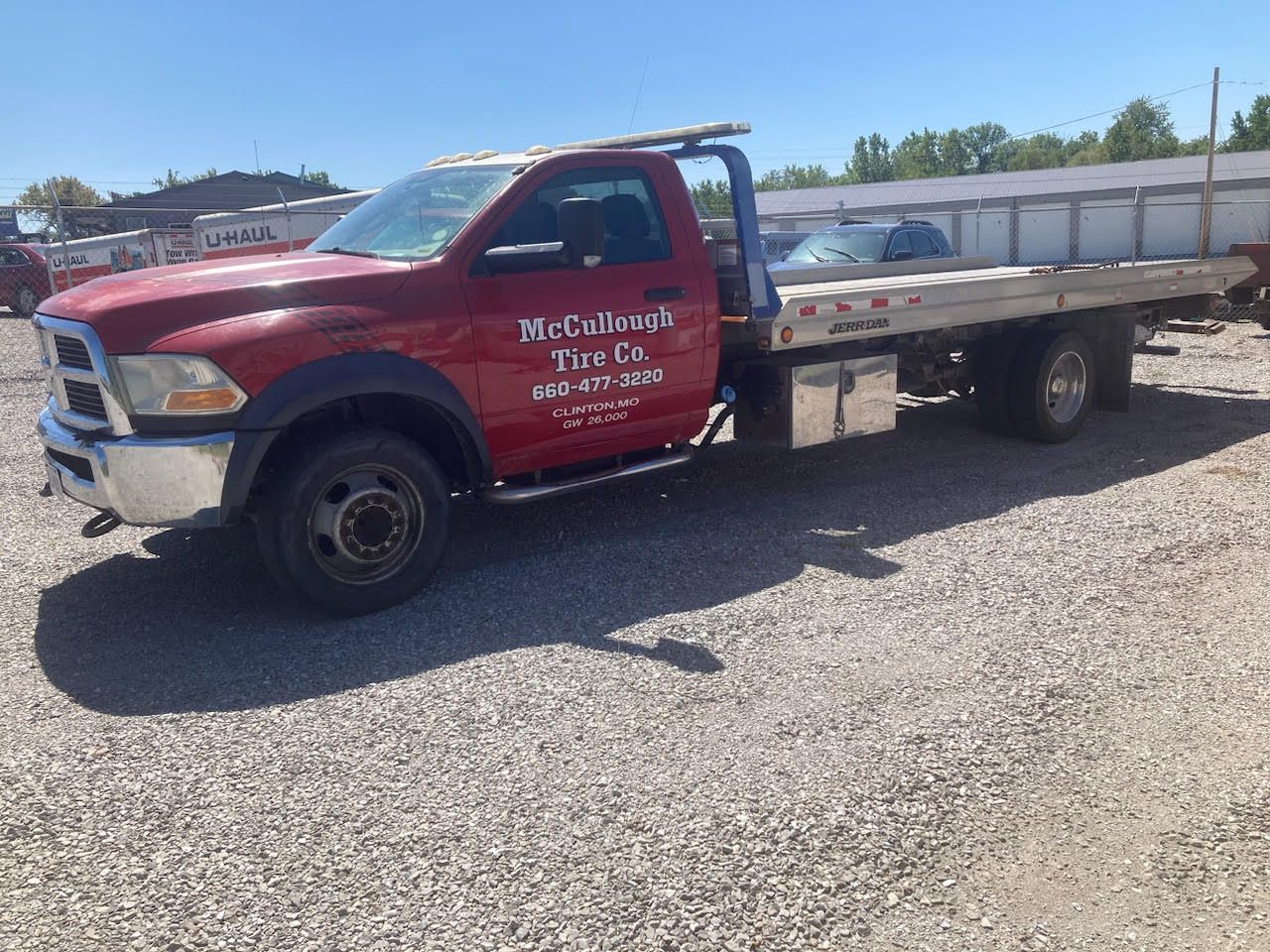 Tow truck carrying a silver SUV on a road, with trees and a yellow fire hydrant visible.