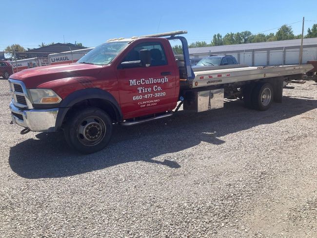 Tow truck carrying a silver SUV on a road, with trees and a yellow fire hydrant visible.
