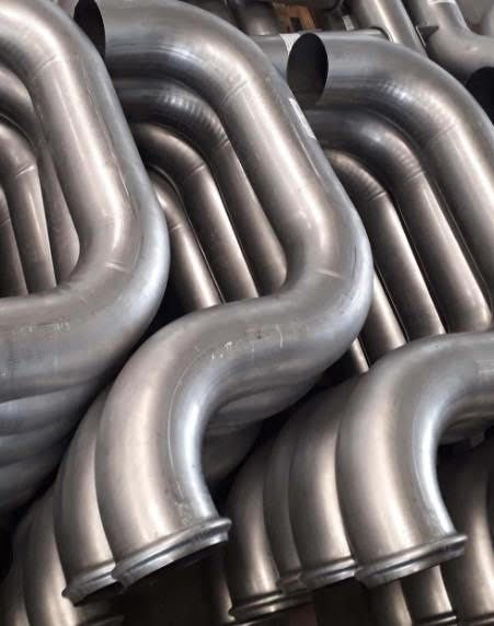 Close-up of a stack of bent metal tubes, likely automotive exhaust pipes, with a silvery finish.