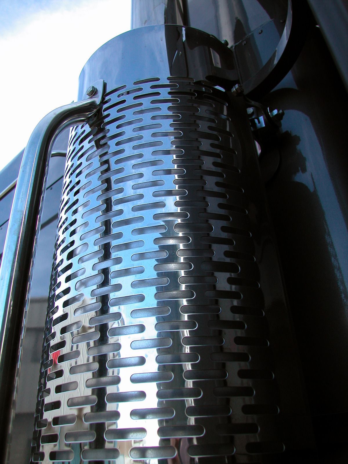 Red car on a white tow truck, parked on a road with green trees in the background.
