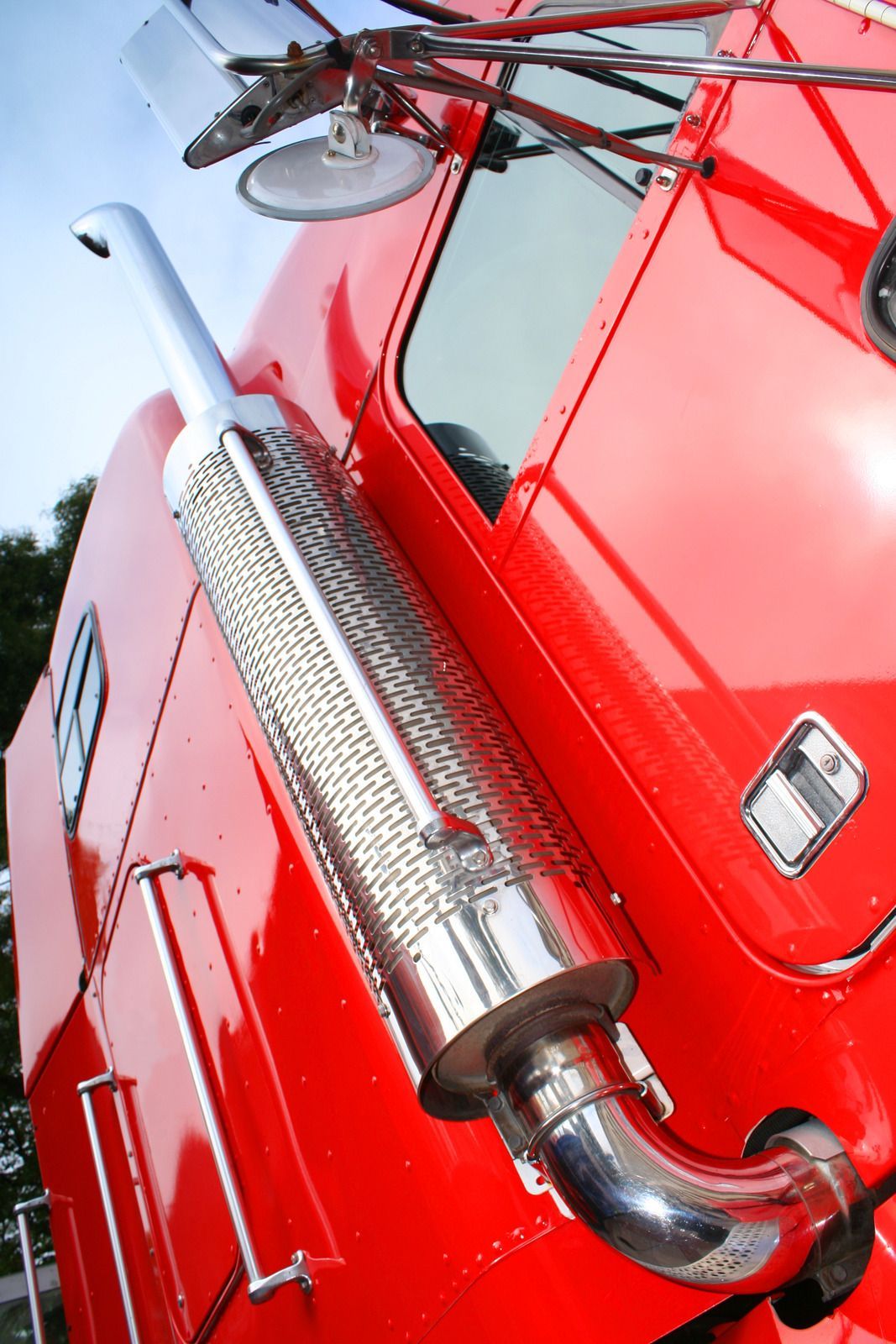 Yellow tow truck carrying a black car on a sunny street.