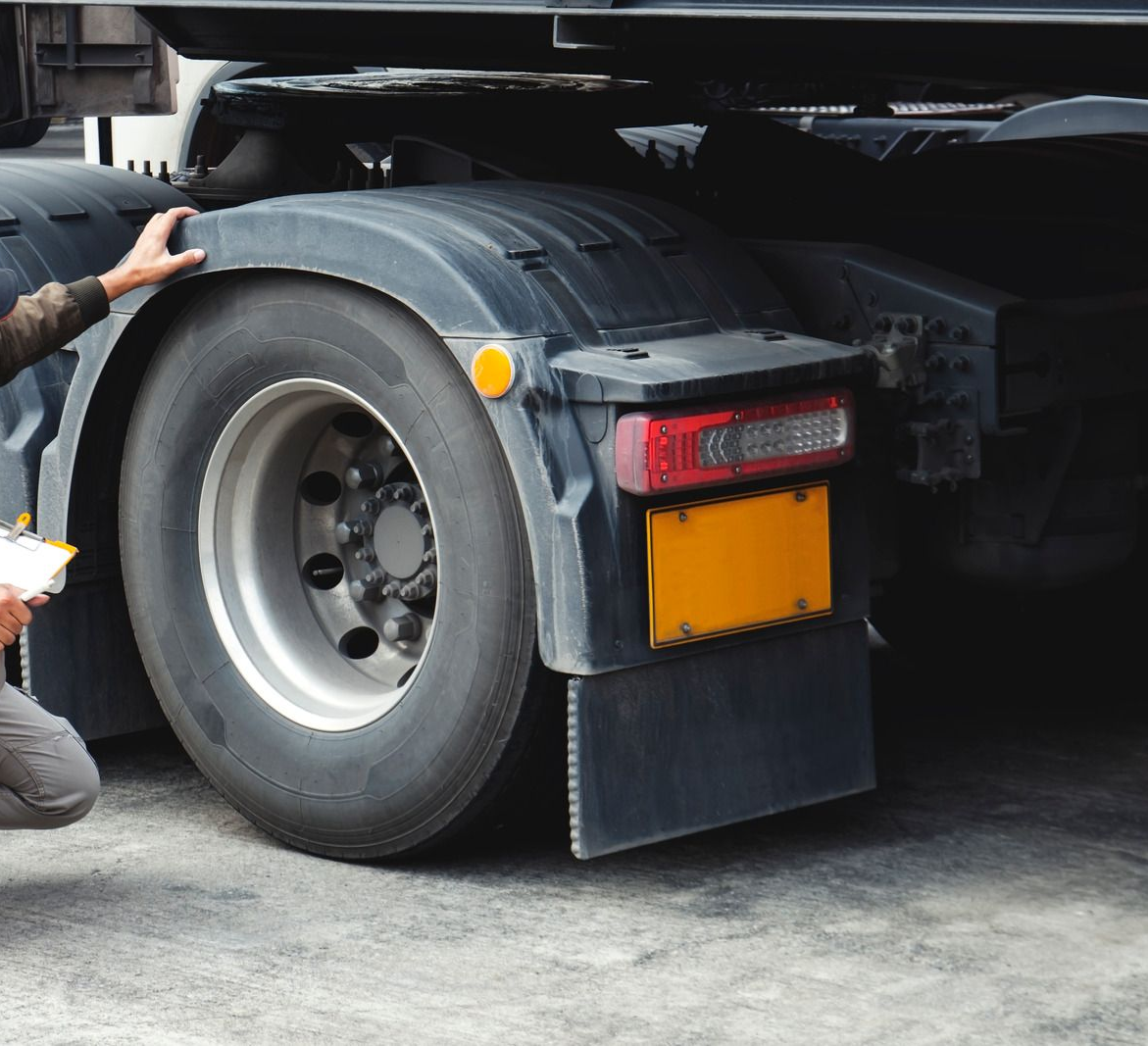 Yellow tow truck carrying a black car on a sunny street.